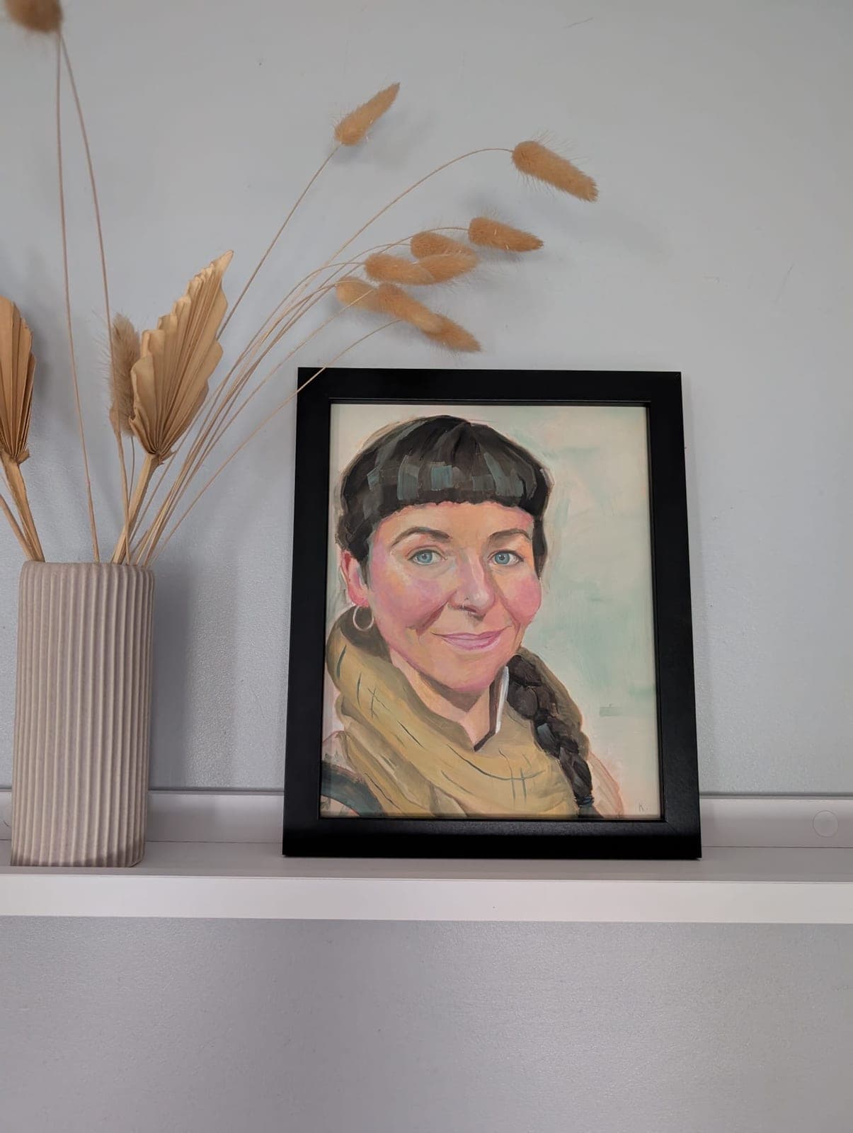 Framed, on a shelf beside dried grasses