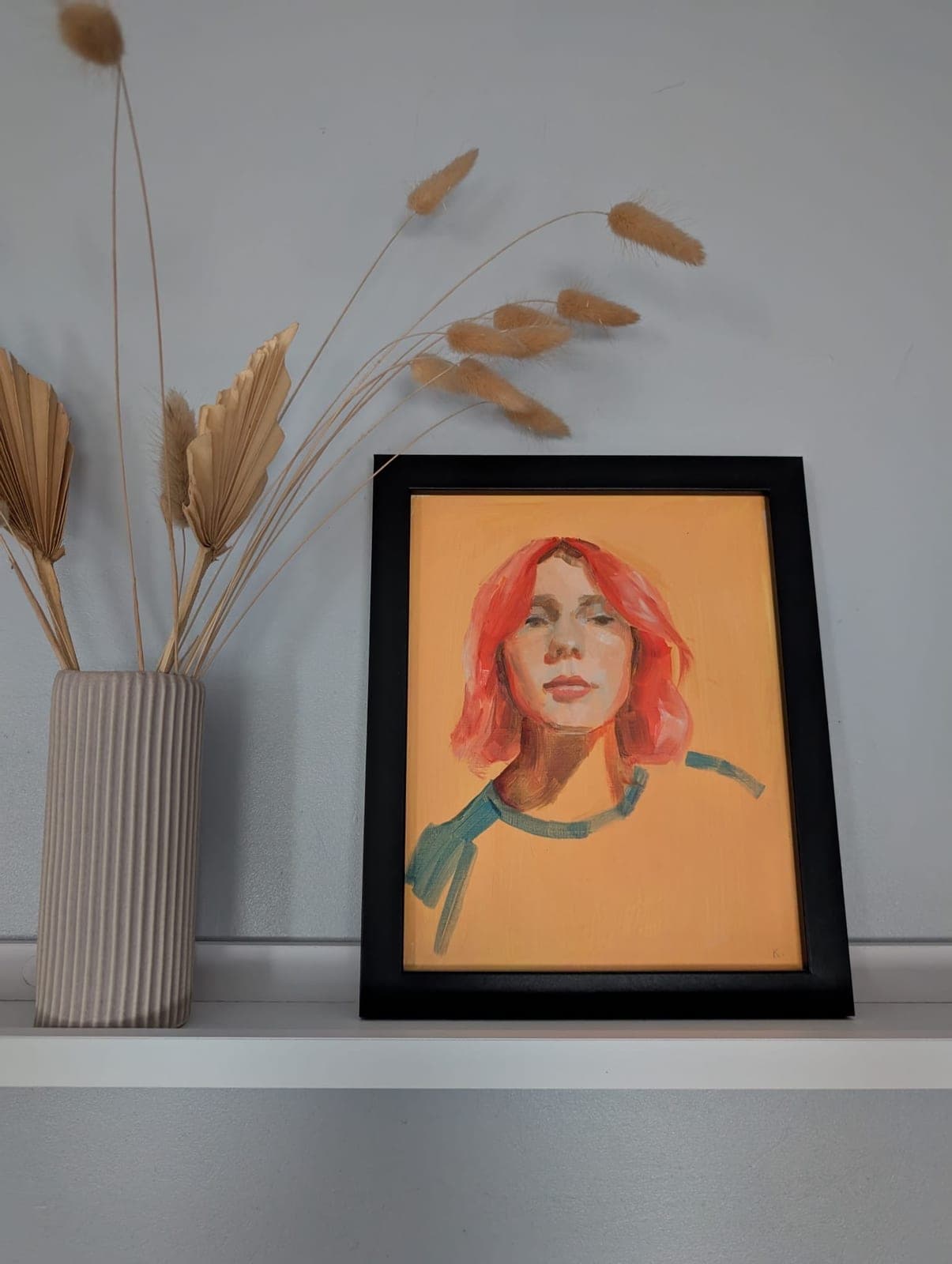 Framed, on a shelf beside dried grasses